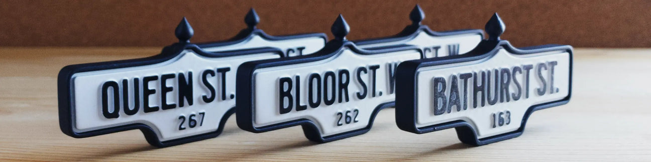 Three acorn street signs: 267 Queen St. W., 262 Bloor St. W., and 163 Bathurst St.