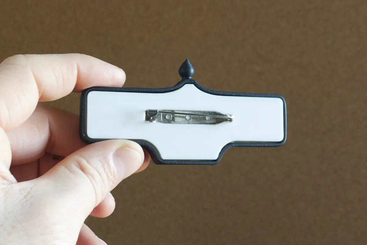 In-hand view (back) of De Grassi St. #119 Pin - Standard Finish, miniature replica Toronto acorn street sign
