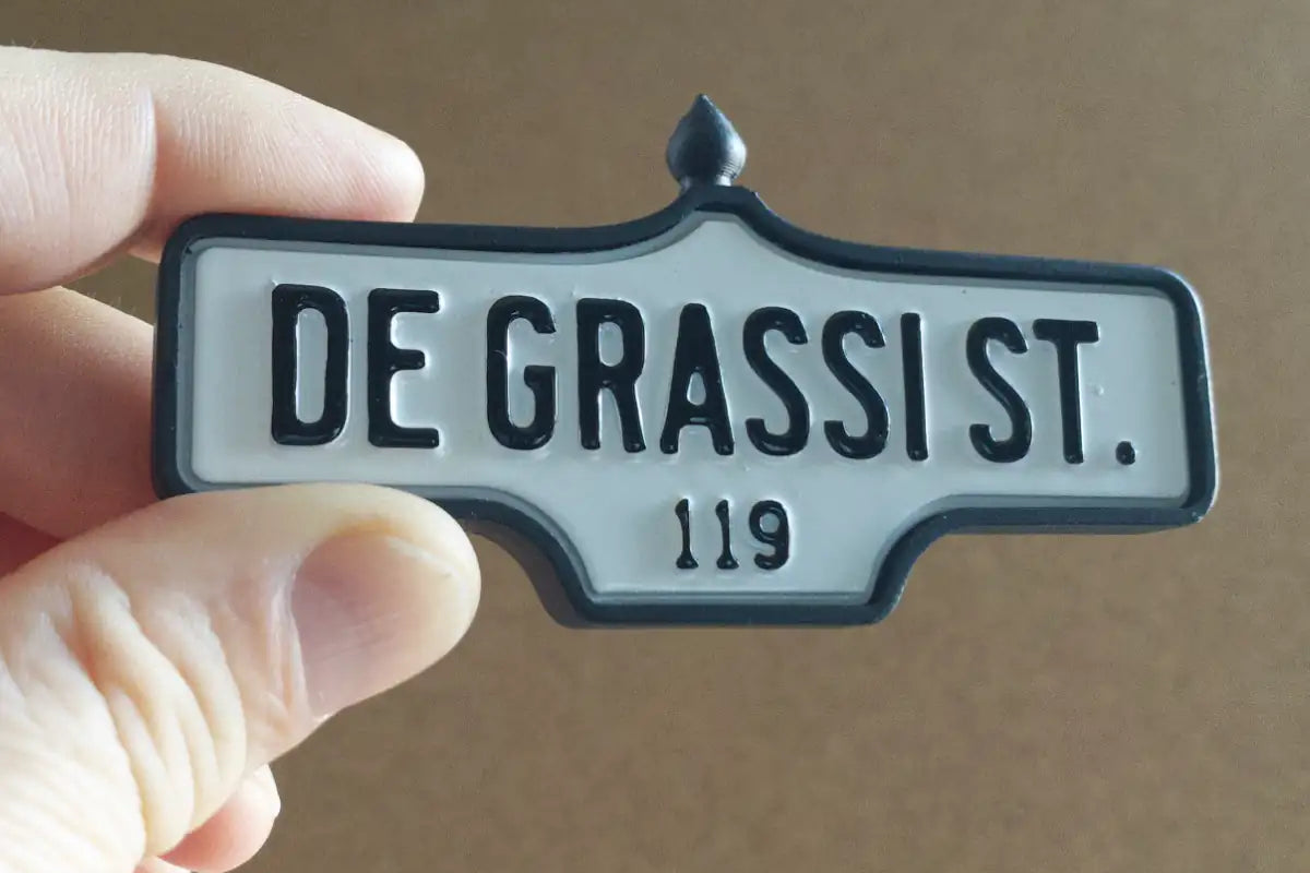 In-hand view of De Grassi St. #119 Pin - Standard Finish, miniature replica Toronto acorn street sign