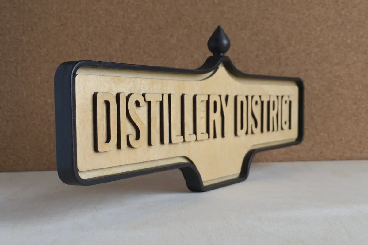 Angled front view of Distillery District Wall Sign - Natural Finish, wall-mounted replica Toronto acorn neighbourhood sign