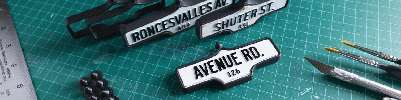 Three acorn street signs on a cutting mat with tools