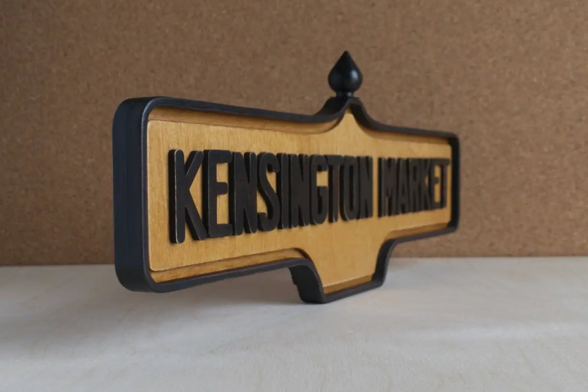 Angled front view of Kensington Market Wall Sign - Natural Finish, wall-mounted replica Toronto acorn neighbourhood sign