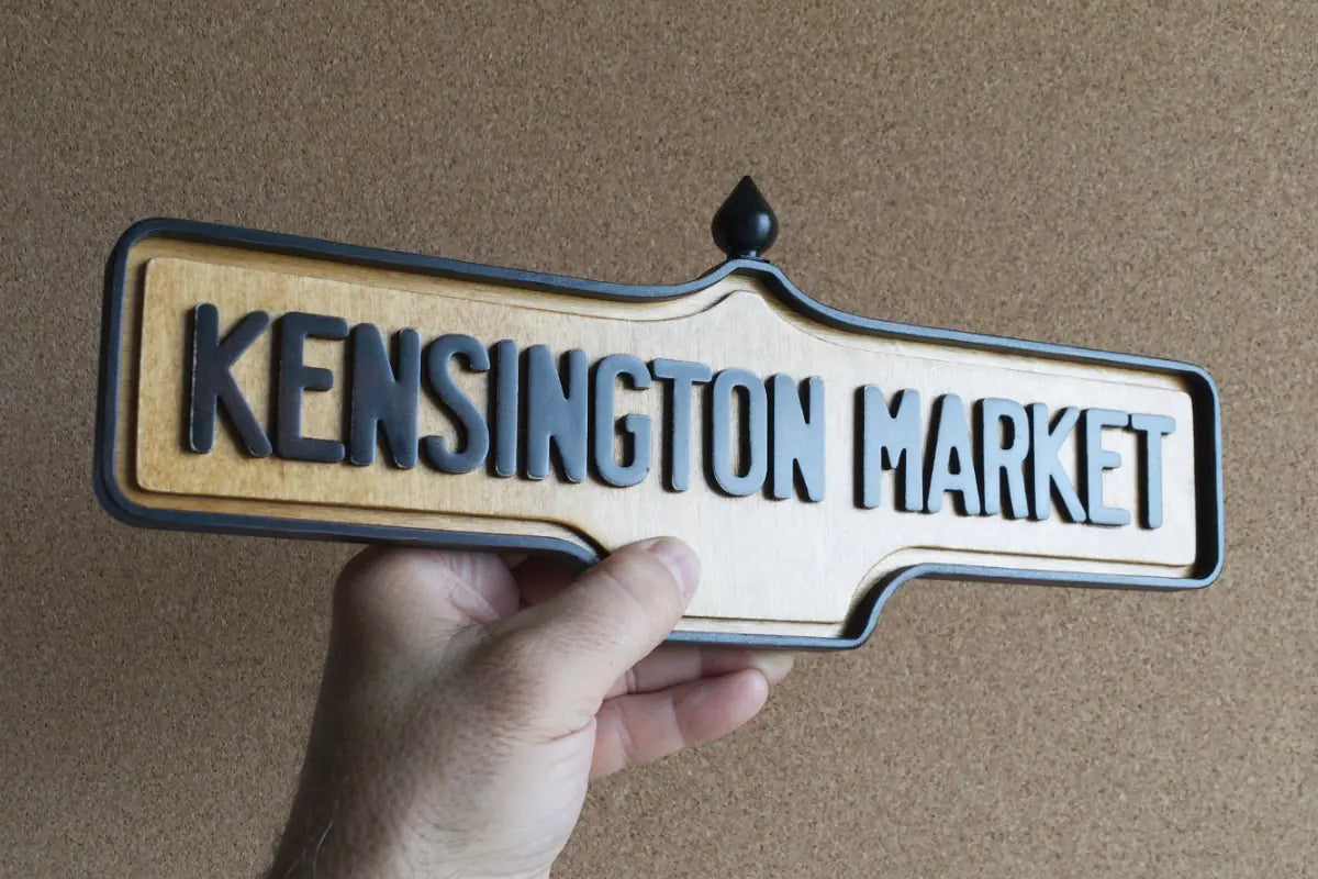 In-hand view of Kensington Market Wall Sign - Natural Finish, wall-mounted replica Toronto acorn neighbourhood sign