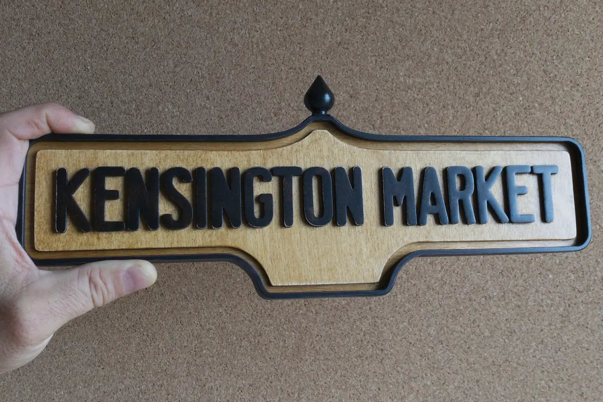 In-hand view of Kensington Market Wall Sign - Natural Finish, wall-mounted replica Toronto acorn neighbourhood sign