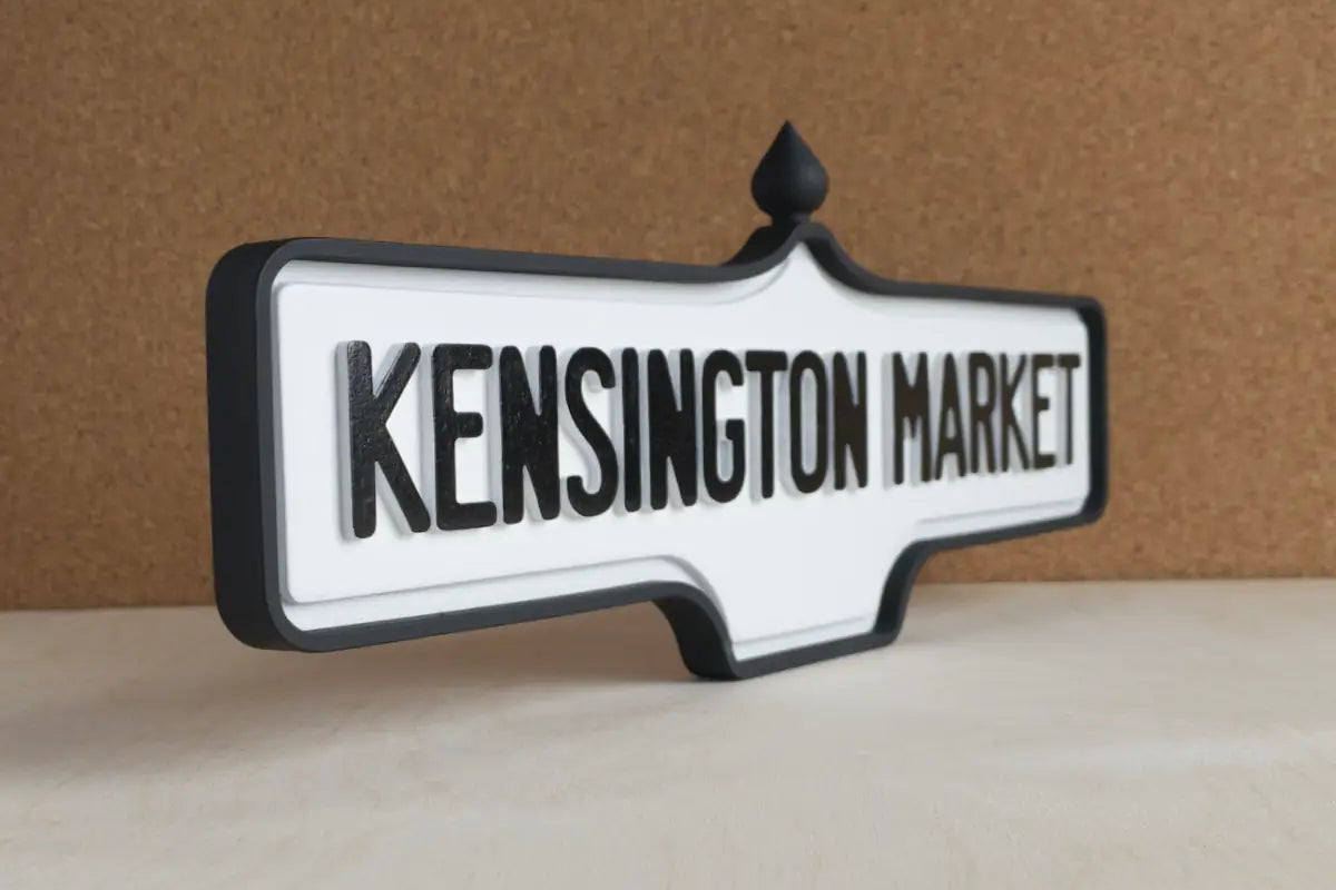 Angled front view of Kensington Market Wall Sign - Standard Finish, wall-mounted replica Toronto acorn neighbourhood sign