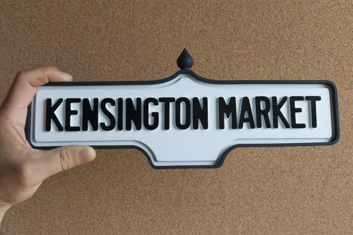 In-hand view of Kensington Market Wall Sign - Standard Finish, wall-mounted replica Toronto acorn neighbourhood sign